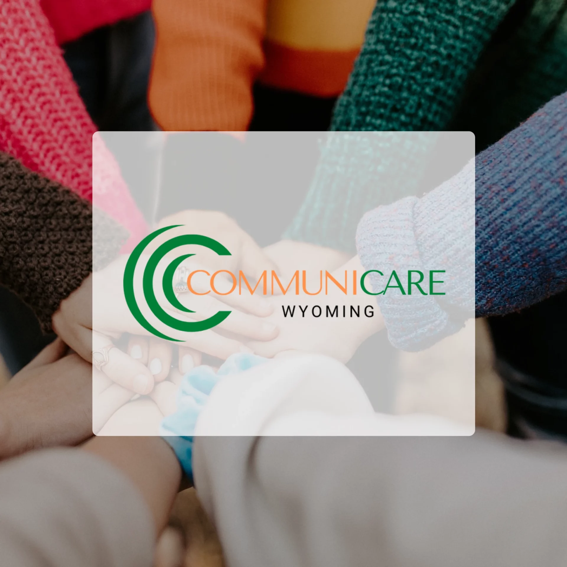 Stacked hands meeting in the center of a group circle. The CommuniCare Wyoming logo is the center focal point in front of the image.
