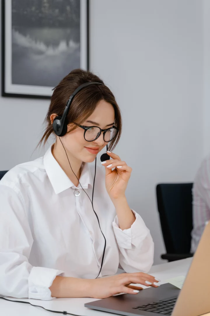 Female call operator with a black headset seated in front of a computer answering a call