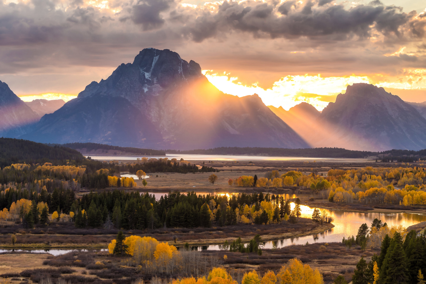 Wyoming mountains with the sun setting behind it with a fall landscaping in front of the mountain